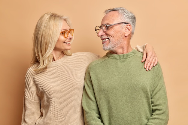 Caring middle aged woman embraces her husband looks with love and broad smile