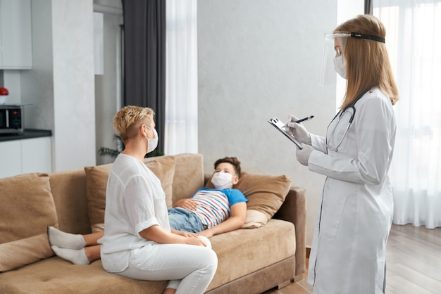 Caring mother sitting near son while doctor doing checkup