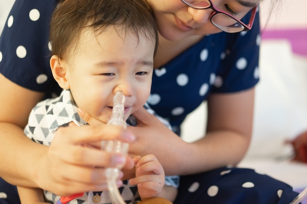 赤ちゃんの鼻をきれいにするために鼻ポンプで思いやりのある母親 鼻分泌物 コロナウイルスの症状 Covid 19の概念 プレミアム写真