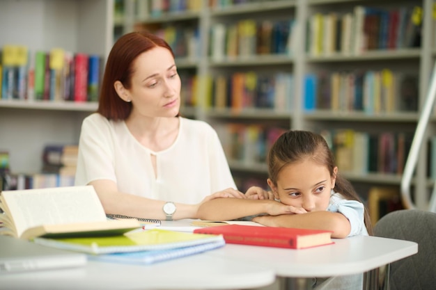 Caring woman touching hand of girl tired of studying