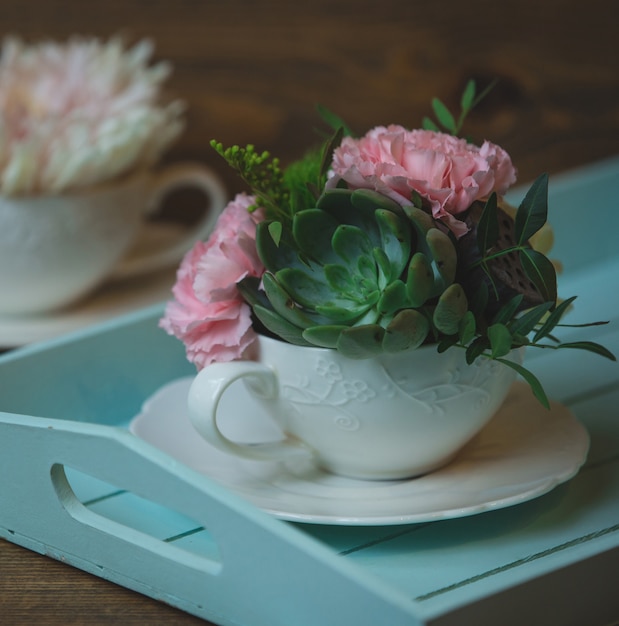 Carnations and suculents in a white ceramic cup
