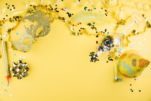 파티 장식 재료와 노란색 배경에 파티 모자와 카니발 깃털 마스크