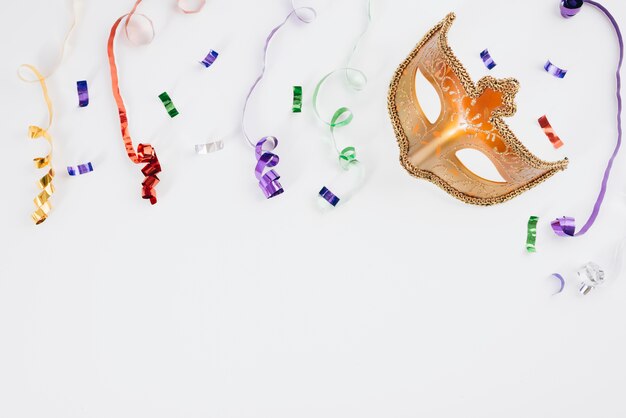 Carnival mask with colourful ribbons on table