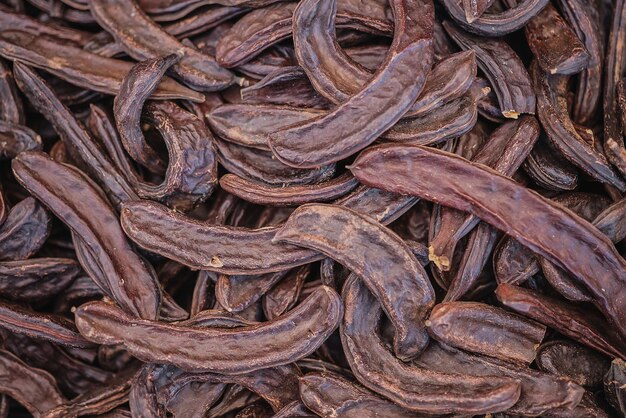 Carob tree pods on a wooden table top view closeup Healthy Organic Sweet Carob Pods