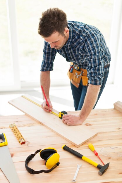 Carpenter checking dimensions of wooden plank