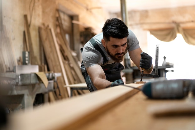 Free photo carpenter cutting mdf board inside workshop