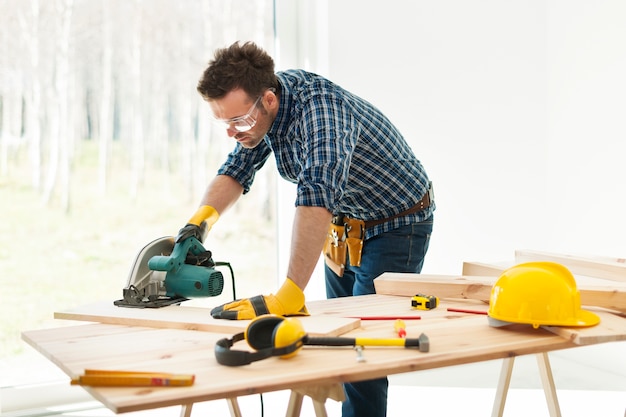 Carpenter cutting plank by circular saw