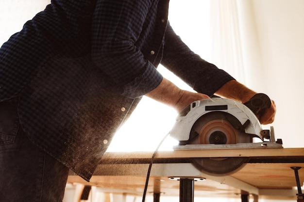 Carpenter hands cutting wood with electrical saw