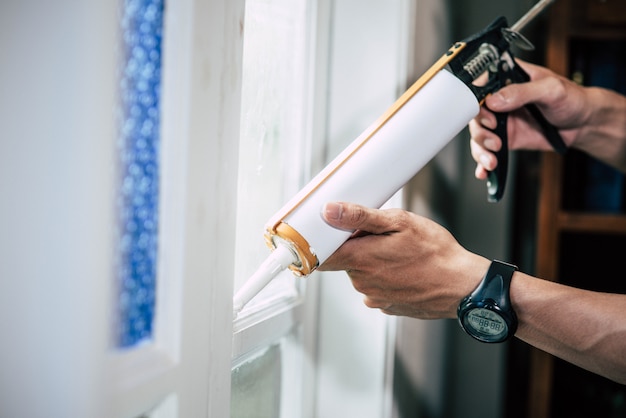 The carpenter holds the glue and attaches to the window.