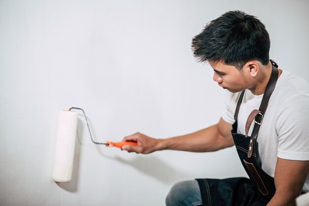 A carpenter holds a paintbrush and paints wood.