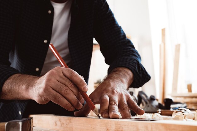 Carpenter makes pencil marks on a wood plank