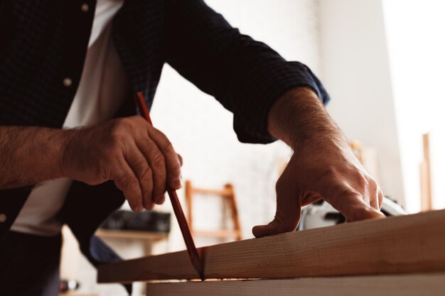 Carpenter makes pencil marks on a wood plank