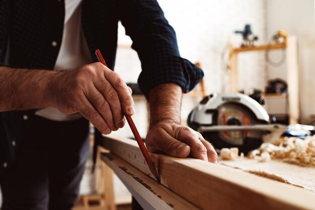 Carpenter makes pencil marks on a wood plank