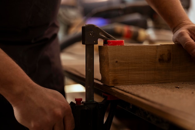 Carpenter using bench vise to hold timber block starting furniture assembling