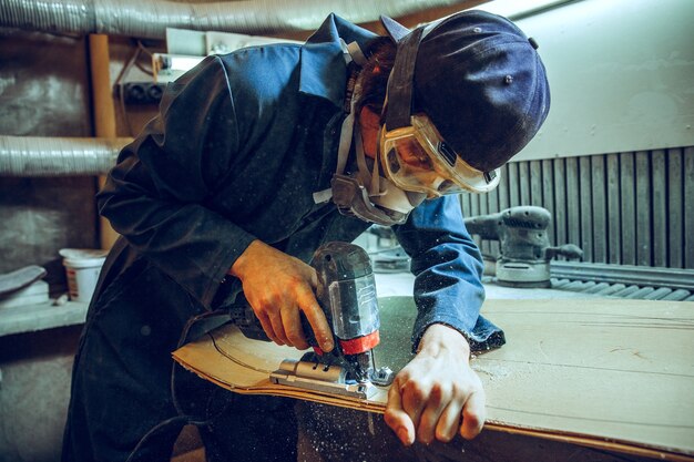 木の板を切るために丸鋸を使用する大工。電動工具を持った男性労働者または便利屋の構造の詳細