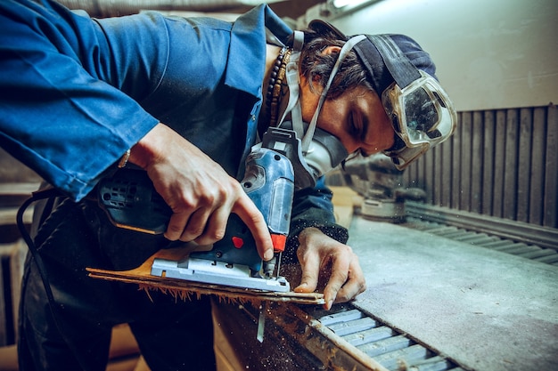 Carpenter using circular saw for cutting wooden boards. Construction details of male worker or handy man with power tools