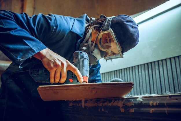 木の板を切るために丸鋸を使用する大工。電動工具を持った男性労働者または便利屋の構造の詳細