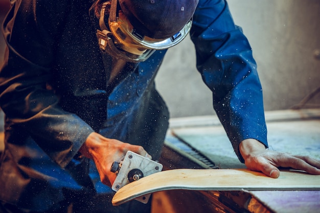 Carpenter using circular saw for cutting wooden boards. Construction details of male worker or handy man with power tools