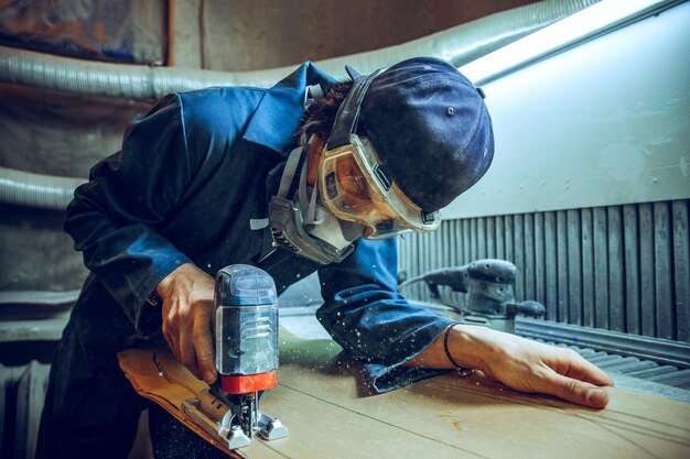 木の板を切るために丸鋸を使用する大工。電動工具を持った男性労働者または便利な男性の構造の詳細