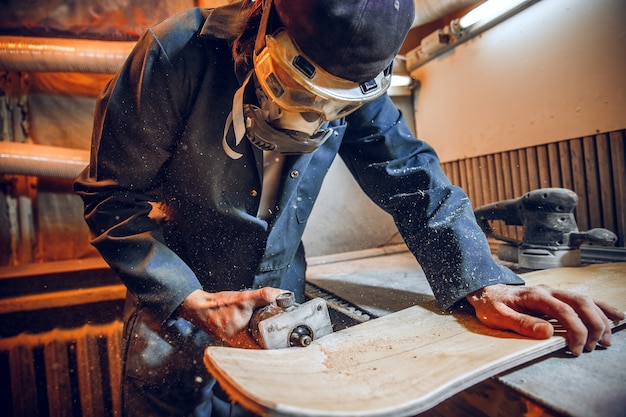 木の板を切るために丸鋸を使用する大工。電動工具を持った男性労働者または便利な男性の構造の詳細