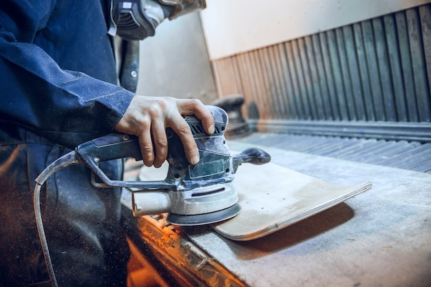 Foto gratuita falegname utilizzando una sega circolare per il taglio di assi di legno. dettagli costruttivi del lavoratore di sesso maschile o uomo a portata di mano con utensili elettrici