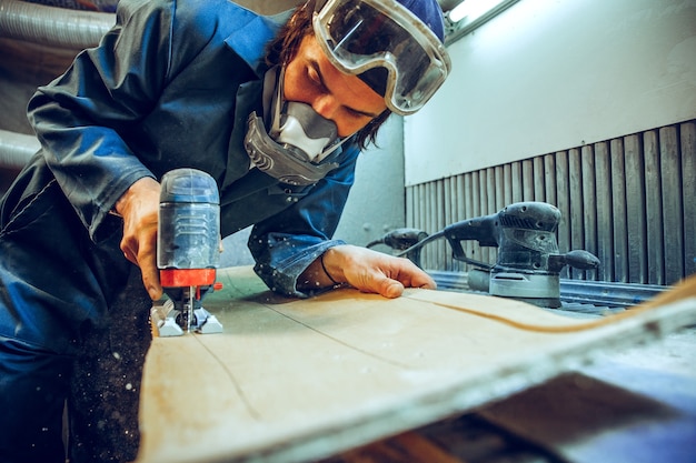 Carpenter using circular saw for cutting wooden boards.