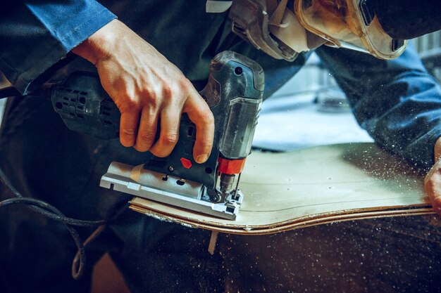 Carpenter using circular saw for cutting wooden boards