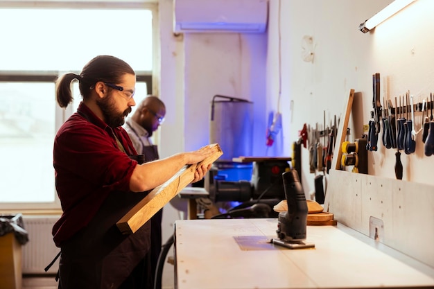 Carpenter wearing protection glasses checking for scratches on wood