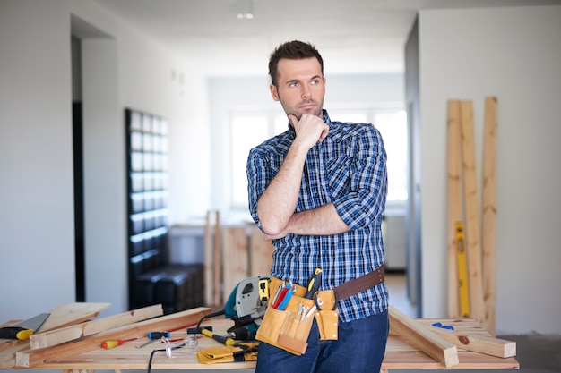 Carpenter working in a house and thinking