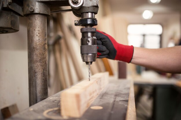 Carpentry workshop and drilling machine working on a piece of wood material