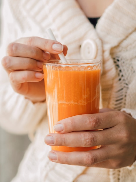 Carrot juice glass in woman hands