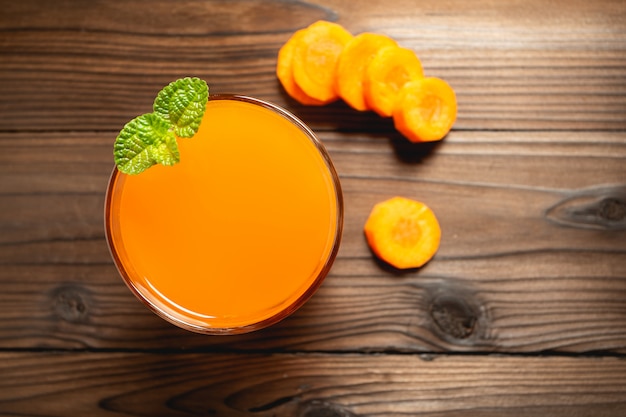 Carrot juice in glass on wooden table.