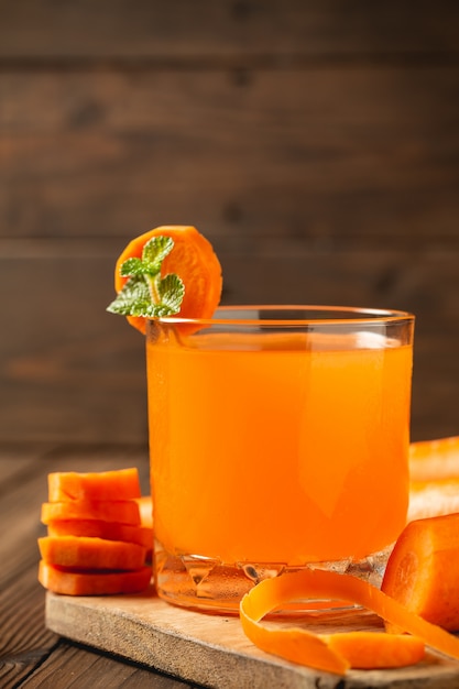 Carrot juice in glass on wooden table.