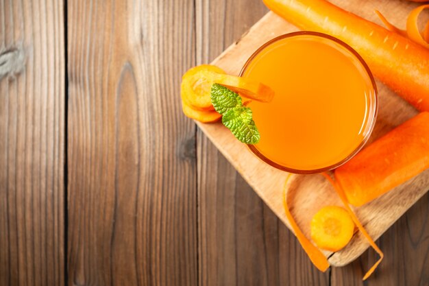 Carrot juice in glass on wooden table.