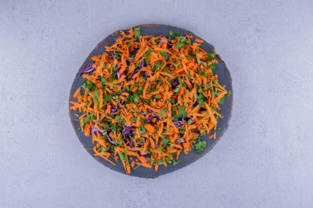 Carrot and red cabbagte chopped into a salad on a board on marble background. High quality photo