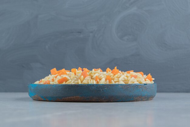 Рис с морковью в деревянной тарелке, на мраморе.