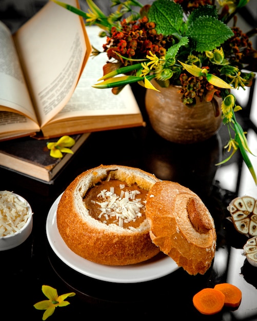 Carrot soup with garlic in bread bowl garnished with cheese