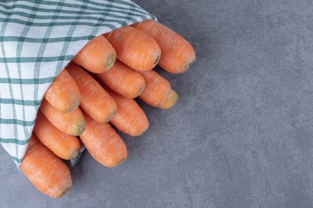 Free photo carrots wrapped in a towel, on the marble surface.