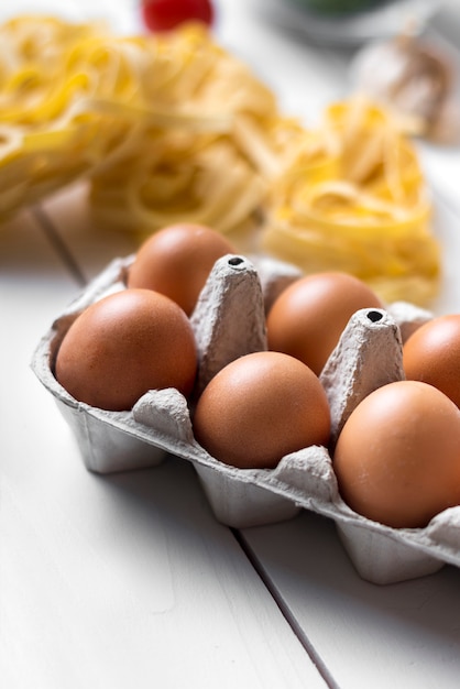 Carton of brown egg on wooden surface