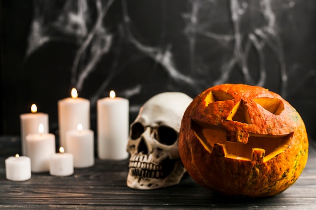 Carved pumpkin and human skull with candles