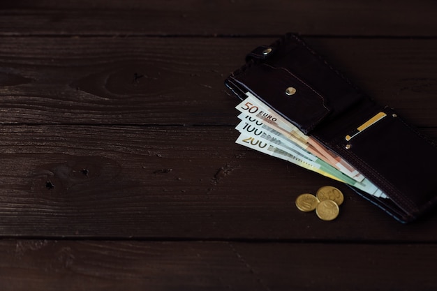 Cash in wallet. Euro cash in brown wallet on wooden background