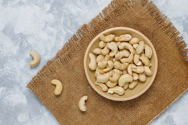 Free photo cashew nuts in ceramic plate on concrete .top view