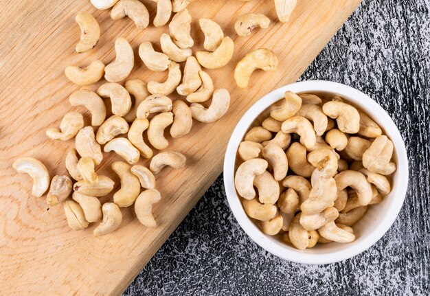 Cashew in white bowl on wooden board