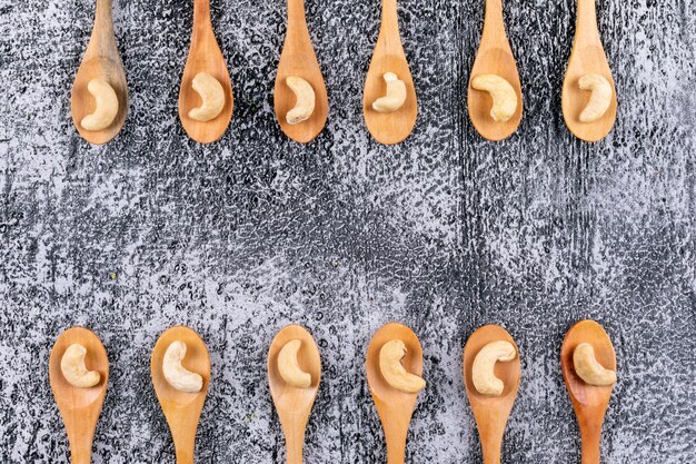 Cashews in a wooden spoon top view on a grey table