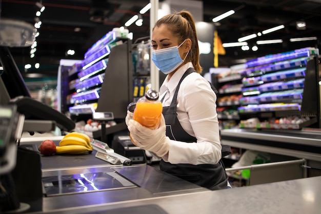 코로나 바이러스로부터 완전히 보호되는 마스크와 장갑을 착용 한 슈퍼마켓의 계산원