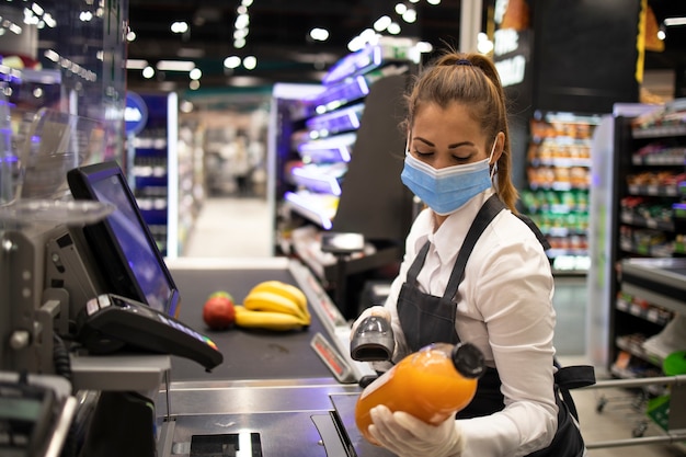 コロナウイルスから完全に保護されたマスクと手袋を着用したスーパーマーケットのレジ係