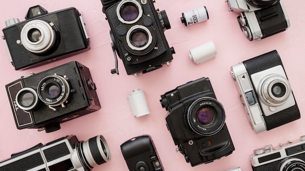 Cassettes amidst cameras on pink background