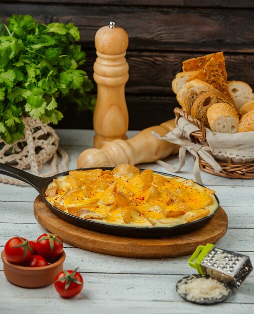 cast iron pan of fried potatoes with eggs served with bread and cheese