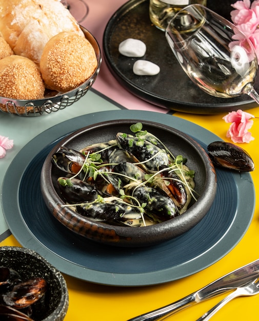 Free photo cast iron pan of mussels in cream sauce garnished with fresh herbs