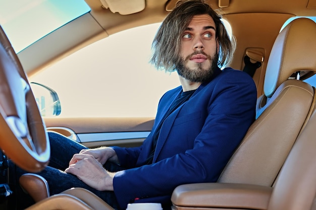 Случайный бородатый мужчина с длинными волосами в машине.